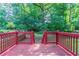A wood deck and red railings give way to a charming lawn view with mature trees at 233 Clayton St, Fairburn, GA 30213