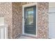 Close-up of a stylish front door with glass pane and brick surround at 123 Matson Sw Run, Mableton, GA 30126