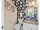 Charming powder room showcases floral wallpaper, granite countertops, and decorative mirror and sconces at 2166 Carlyle Dr, Marietta, GA 30062