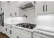 Close-up of modern kitchen featuring white cabinets, black hardware, and a gas cooktop with stylish backsplash at 2381 Jones Phillips Rd, Dacula, GA 30019