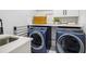 A modern laundry room with stainless steel sink, blue washer and dryer at 2381 Jones Phillips Rd, Dacula, GA 30019