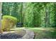 A view of the backyard with a stone walkway and a trampoline amidst the lush trees at 245 Ashley Forest Dr, Fayetteville, GA 30214