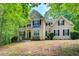 Stately two-story home featuring a symmetrical facade, black shutters, and lush, mature landscaping at 245 Ashley Forest Dr, Fayetteville, GA 30214