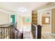 Hallway featuring hardwood floors, iron banister, built-in shelves, and natural light at 245 Ashley Forest Dr, Fayetteville, GA 30214