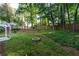 Expansive backyard featuring a stone fire pit, mature trees, and a covered patio with a white pergola at 755 Waterbrook Ter, Roswell, GA 30076