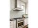 Close-up of a kitchen featuring a stainless steel range hood and stone backsplash at 775 A Harrison Se Pl, Atlanta, GA 30315