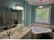 Bathroom with blue walls, decorative window, soaking tub, shower, and and vanities at 1042 Emory Parc Pl, Decatur, GA 30033