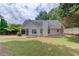 Back of home showcasing a covered patio and expansive backyard with lush greenery at 627 New England Way, Lawrenceville, GA 30046