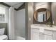 Cozy bathroom features a shower-tub combo, white tiled walls, and a vanity with a round mirror at 622 Seminole Ne Ave, Atlanta, GA 30307