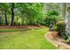 Expansive backyard featuring lush grass, mature trees, and a charming wooden patio area at 2425 Hamptons Psge, Alpharetta, GA 30005