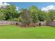 A beautiful backyard features a well-maintained lawn, trees, bushes and a privacy fence at 5225 Stonehaven Vw, Cumming, GA 30040