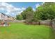 A backyard features a well-maintained lawn, a wooden privacy fence, lush trees and some playground equipment at 5225 Stonehaven Vw, Cumming, GA 30040