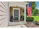Inviting front porch with stone accents, decorative plants, a stylish front door, and an American flag at 5225 Stonehaven Vw, Cumming, GA 30040