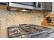 Kitchen close-up highlighting the stainless steel stove, mosaic backsplash, and granite countertops at 5225 Stonehaven Vw, Cumming, GA 30040