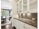 Butler's pantry featuring granite countertops, tile backsplash, and glass-front cabinetry at 1393 Kings Park Nw Dr, Kennesaw, GA 30152