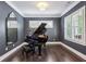 Elegant living room with dark grey walls, hardwood floors, and a grand piano at 1393 Kings Park Nw Dr, Kennesaw, GA 30152