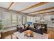 Open concept living room with exposed beams, plantation shutters, and view of the connected kitchen at 970 N Ormewood Park Se Dr, Atlanta, GA 30316