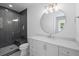 Modern bathroom featuring a walk-in shower, white vanity, and a large round mirror at 126 Owens Mill Pl, Canton, GA 30115