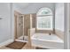 A bright bathroom featuring a separate shower and tub with a large window at 1255 Hidden Creek Pt, Cumming, GA 30040