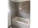 This bathroom features gray square wall tiling and a white bathtub with chrome fixtures at 1730 Fulmont Cir, Mableton, GA 30126
