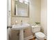 Well-lit half-bathroom with a pedestal sink, toilet, decorative mirror, and neutral wall paint at 510 Morning Mist Ct, Alpharetta, GA 30022