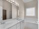 Bright bathroom featuring a double vanity and soaking tub with a grid-patterned window at 127 Autumn Run Pl, Villa Rica, GA 30180