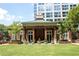 Beautiful clubhouse with brick facade, green roof, and lush landscaping sits in front of a modern high-rise building at 1820 Peachtree Nw St # 309, Atlanta, GA 30309