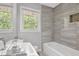 Modern bathroom featuring a tub, sleek gray tile, and natural light from two windows at 2636 Flagstone Se Dr, Atlanta, GA 30316