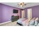 Bedroom with purple walls, dark gray furniture, and a plush bed is illuminated by a ceiling fan at 3860 Overlake Dr, Cumming, GA 30041