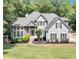 Charming two-story home with manicured lawn, stone accents, and gray siding nestled among lush trees at 3860 Overlake Dr, Cumming, GA 30041