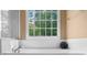Bright bathroom featuring a soaking tub beneath a large window with tiled surround at 7049 Bennington Ln, Cumming, GA 30041