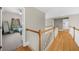 A bright hallway leads to a bedroom and bathroom, featuring hardwood floors and white railings at 7049 Bennington Ln, Cumming, GA 30041