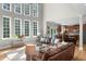 Elegant living room featuring hardwood floors, large windows, and a peek into the kitchen area at 7049 Bennington Ln, Cumming, GA 30041