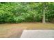 Lush and green backyard featuring mature trees, lawn, and a concrete patio at 2557 Woodford Ln, Buford, GA 30519