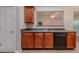Cozy kitchen featuring cherry wood cabinets, a black dishwasher, and view to living room at 2557 Woodford Ln, Buford, GA 30519