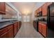 Functional kitchen featuring cherry wood cabinets, black appliances, and an open layout to dining room at 2557 Woodford Ln, Buford, GA 30519