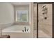 Bright bathroom featuring a soaking tub next to a separate shower with black trim and bright window at 165 Brookstone E Park, Acworth, GA 30101