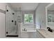 Modern bathroom featuring a glass shower, soaking tub, and a sleek vanity with black fixtures at 3668 Burel Mill Dr, Buford, GA 30519