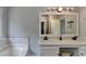 Bright bathroom featuring double sinks, marble counters, and a large mirror with decorative lighting at 3668 Burel Mill Dr, Buford, GA 30519