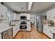 Bright kitchen features white cabinetry, stainless steel appliances, and hardwood floors with an adjacent dining area at 3668 Burel Mill Dr, Buford, GA 30519