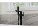 Modern bathtub features a stylish matte black faucet and neutral tile surround at 5567 Tyree Rd, Winston, GA 30187