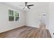 Bright bedroom featuring wood floors, a modern ceiling fan, and a window with a view of the wooded exterior at 5567 Tyree Rd, Winston, GA 30187