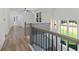 Second floor hallway with wood railing, black iron spindles, wood floors, and large sunny windows at 5567 Tyree Rd, Winston, GA 30187