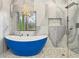 Elegant bathroom with a blue soaking tub, decorative tile shower, and modern chandelier at 1355 Lockwood Sw Dr, Atlanta, GA 30311