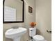 Clean and simple bathroom featuring a pedestal sink, a toilet, a framed mirror, and neutral décor at 4581 Sagebrush Ct, Snellville, GA 30039