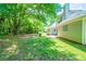 A grassy backyard with mature trees and the side of a gray home at 297 Edison Dr, Stockbridge, GA 30281