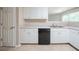 View of the kitchen featuring a black dishwasher, sink, and white cabinets at 297 Edison Dr, Stockbridge, GA 30281
