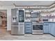 Updated kitchen features stainless steel appliances, blue cabinets, floating shelves, and fireplace access at 215 Little Brook Ln, Woodstock, GA 30188