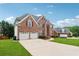 Expansive two-story brick home with a long driveway leading to a two car garage and landscaped front yard at 2372 Wilshire Way, Douglasville, GA 30135