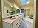 Bright bathroom featuring double sinks, white cabinets, and a luxurious soaking tub with natural light from a skylight at 2694 Tritt Springs Ne Dr, Marietta, GA 30062